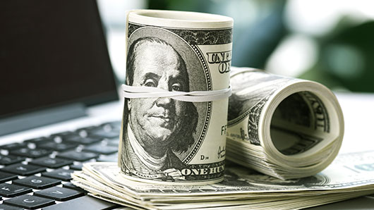 Roll of cash on laptop